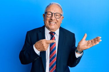 Beyaz üst düzey bir adam iş elbisesi giyiyor ve kameraya hayret içinde bakıyor ve gülümsüyor.. 