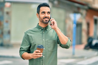 Genç İspanyol adam akıllı telefondan konuşuyor. Şehirde kahve içiyor..