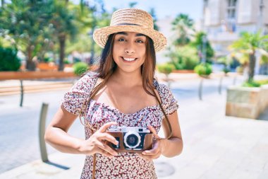 Şehrin caddesinde gezen eski model kamera kullanan genç Latin kadın..