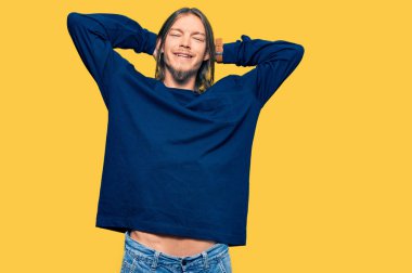 Uzun saçlı yakışıklı beyaz adam... günlük kışlık süveter giyiyor... rahatlıyor ve esniyor, kolları ve elleri başının arkasında... ve boynunun arkasında gülümsüyor. 