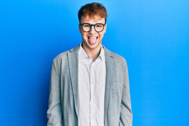 Zarif kıyafetler giyen ve gözlüklü genç beyaz adam komik bir ifadeyle dilini dışarı çıkartıyor. duygu kavramı. 