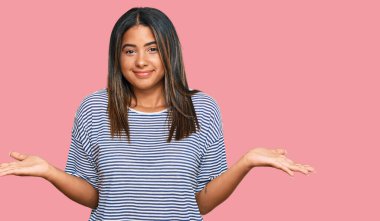 Gündelik kıyafetler giyen, elleri ve kolları havada, kafası karışmış genç Latin kız. şüphe kavramı. 