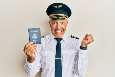 Yakışıklı orta yaşlı yetişkin pilot, pasaportunu tutuyor gururla bağırıyor, zaferi kutluyor ve başarıyı kollarını kaldırarak kutluyor. 