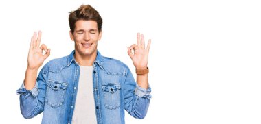 Sıradan kot ceket giyen yakışıklı beyaz adam rahatla ve parmaklarıyla meditasyon hareketi yaparken gözleri kapalı gülümse. yoga konsepti. 