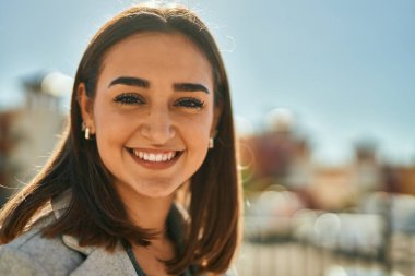 Genç İspanyol kız gülümseyerek şehirde mutlu mesut dikiliyor..