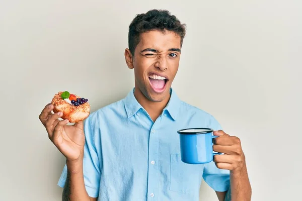 Young Handsome African American Man Drinking Coffee Eating Pastry Winking — Stock Photo, Image