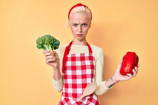 Mujer Rubia Joven Con Tatuaje Usando Delantal Cocinero Sosteniendo Brócoli —  Fotos de Stock