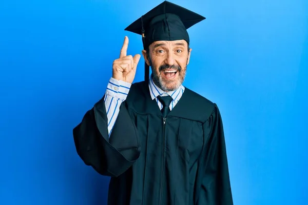 卒業キャップと式のローブを身に着けている中年のパニック男は 成功したアイデアで指を指しています 興奮して幸せよ 第1位 — ストック写真
