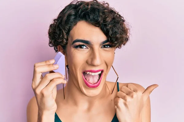 Joven Hombre Vistiendo Mujer Maquillaje Celebración Esponja Apuntando Pulgar Hasta —  Fotos de Stock