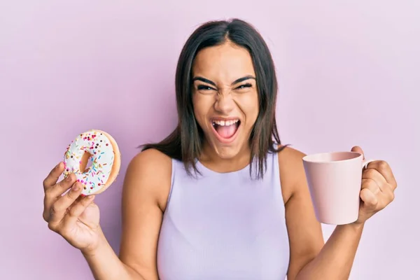 Mujer Morena Joven Comiendo Donut Tomando Café Celebrando Loco Sorprendido —  Fotos de Stock