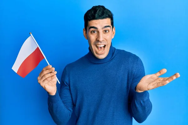 Hombre Hispano Guapo Sosteniendo Bandera Polonia Celebrando Logro Con Sonrisa —  Fotos de Stock