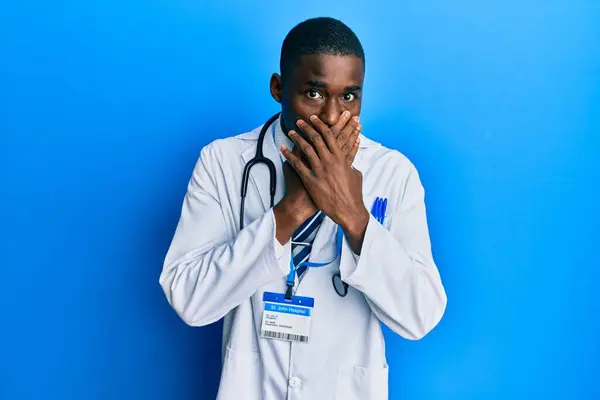 Młody Afrykański Amerykanin Mundurze Doktora Zszokowany Zakryciem Ust Rękami Przez — Zdjęcie stockowe