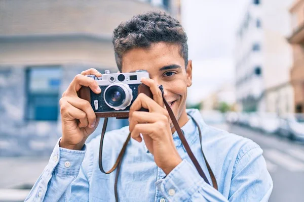 若いですラテン観光の男笑顔幸せな使用してヴィンテージカメラ歩行で街 — ストック写真