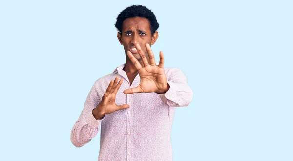 アフリカのハンサムな男は 手で恐怖表現を停止ジェスチャーを恐れて ショックで叫んでカジュアルなピンクのシャツを着ている パニックの概念 — ストック写真
