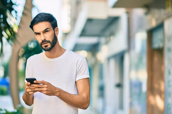 Joven Hombre Hispano Con Expresión Seria Usando Smartphone Ciudad —  Fotos de Stock