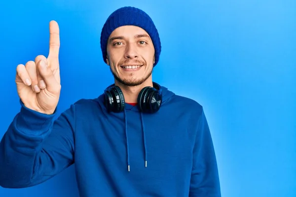 Joven Hispano Usando Sudadera Auriculares Mostrando Señalando Con Dedo Número —  Fotos de Stock