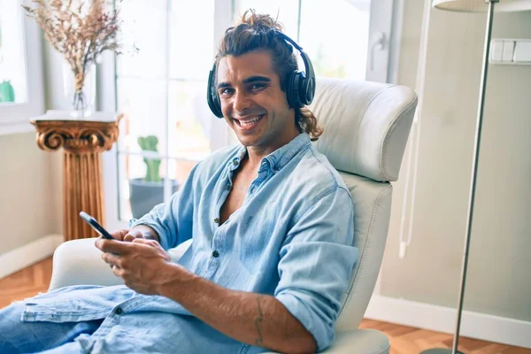 Junger Hispanischer Mann Lächelt Glücklich Mit Smartphone Und Kopfhörer Hause — Stockfoto