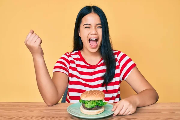 Fiatal Ázsiai Lány Eszik Egy Ízletes Klasszikus Burger Sikoltozó Büszke — Stock Fotó