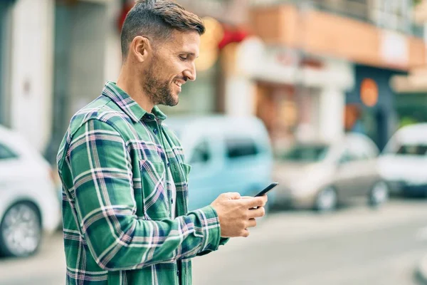 Mladý Kavkazský Muž Usměvavý Šťastný Pomocí Smartphonu Městě — Stock fotografie