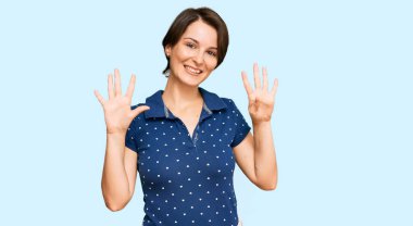 Kısa saçlı, esmer, günlük kıyafetler giyen genç bir kadın dokuz numarayı gösteriyor ve gülümsüyor. Kendinden emin ve mutlu.. 