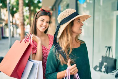 Güzel İspanyol anne ve kızı gülümseyerek şehirde mutlu ve alışveriş yapıyorlar..