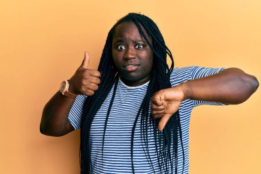 Örgülü genç siyahi bir kadın şok olmuş yüzüne baş parmak işareti yapıyor. Şüpheci, alaycı ve ağzı açık bir şekilde şaşırmış görünüyor. 