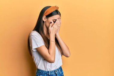 Güzel, esmer, günlük beyaz tişört giyen, suratını ellerle örten ve ağlayan bir kadın. depresyon kavramı. 