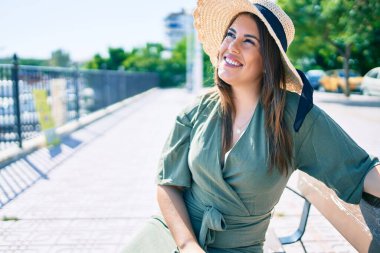 Genç İspanyol kadın tatilde gülümsüyor. Mutlu bir şekilde şehrin sokaklarında bankta oturuyor.