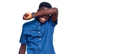 Genç Afro-Amerikan adam günlük kıyafetler giyip kollarıyla gözlerini kapatıyor neşeli ve komik gülümsüyor. kör kavram. 