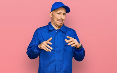 Sakallı, inşaatçı tulumu giyen kel adam tiksindirici ve tiksindirici ifade, tiksindirici yüz ifadesi takınıyor.. 