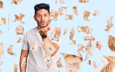 Yakışıklı Latin Amerikalı sıradan tişörtler giyen genç adam kameraya bakıp havada bir öpücük savuruyor ve sevimli ve seksi oluyor. aşk ifadesi.