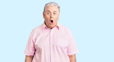 Kıdemli, gri saçlı, günlük kıyafetler giyen, ağzı açık, korkmuş ve şaşırmış bir adam. 