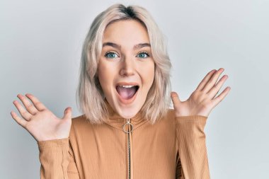 Sıradan kıyafetler giyen genç sarışın kız çılgın ve başarıyı kollarını kaldırıp heyecanla haykırarak kutluyor. Kazanan konsept 