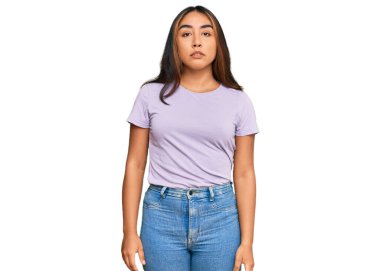 Gündelik kıyafetler giyen genç Latin kadın yüzünde ciddi bir ifadeyle rahatlamış. Basit ve doğal bir şekilde kameraya bakıyorsun.. 