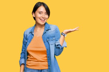 Kısa saçlı, sıradan bir kot ceket giyen, neşeli bir şekilde gülümseyen, elini kaldırıp kameraya bakan genç ve güzel İspanyol bir kadın.. 