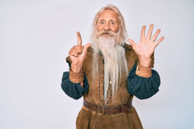 Gri saçlı, uzun sakallı, Viking kostümü giyen ve yedi numaralı parmaklarını gösterip gülümseyen yaşlı bir adam.. 