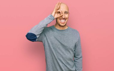 Kel, sakallı, sıradan kıyafetler giyen, el hareketleriyle gülümseyen, mutlu yüzüyle parmaklarından bakan bir adam.. 