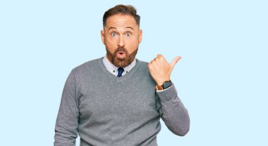 İş kıyafetleri giyen yakışıklı orta yaşlı bir adam elleri yana dönük, ağzı açık şaşkın bir şekilde şaşırdı.. 