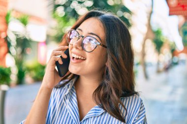 Genç İspanyol iş kadını gülümsüyor. Şehirdeki akıllı telefondan mutlu bir şekilde konuşuyor..