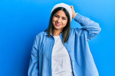 Şirin yün şapka giyen genç Latin kadın kafasını karıştırıyor ve soru soruyor. Şüpheyle kararsız, kafa kafaya düşünerek. Düşünceli kavram. 