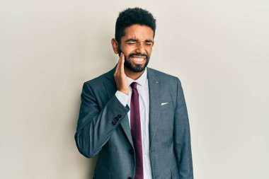 Sakallı ve kravatlı yakışıklı İspanyol bir adam diş ağrısı ya da diş ağrısı yüzünden ağza dokunuyor. dişçi 