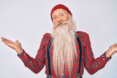 Gri saçlı, uzun sakallı, hippi görünümlü, yün şapkalı, her iki elini de açık gösteren, avuçlarını gösteren, sunan, reklam yapan, karşılaştıran ve dengeli yaşlı bir adam. 