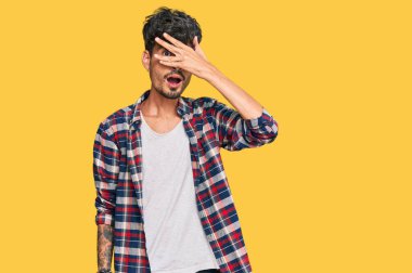 Gündelik kıyafetler giyen genç İspanyol adam şok içinde yüzünü ve gözlerini kapayarak utanmış ifadesiyle parmaklarından bakıyor.. 