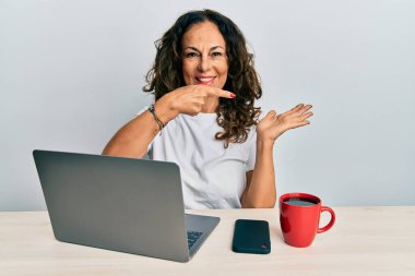 Ofiste çalışan orta yaşlı güzel bir kadın bilgisayarını kullanıyor kameraya hayret ediyor ve gülümsüyor.. 