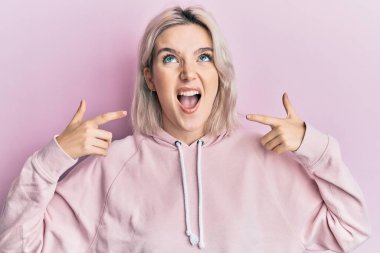 Genç sarışın kız parmaklarıyla ağzını işaret ediyor kızgın ve deli gibi bağırıyor hayal kırıklığına uğramış ve öfkeli, öfkeyle bağırıyor.. 