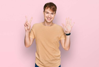 Gündelik giysiler giymiş genç beyaz bir adam 7 numarayı gösterip işaret ederken kendine güvenen ve mutlu bir şekilde gülümsüyor.. 