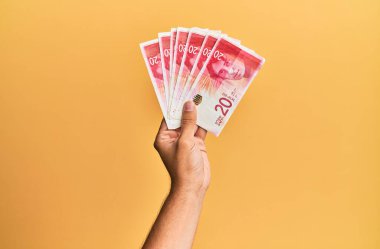 İsrail 'i tutan İspanyol' un eli. 20 şekel banknot, izole edilmiş sarı arka plan..