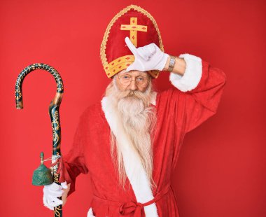 Gri saçlı ve uzun sakallı yaşlı bir adam geleneksel Aziz Nicholas kostümü giyiyor. Alnında parmakları olan insanlarla alay ediyor. Ezik hareketler yapıyor, alay ediyor ve hakaret ediyor.. 