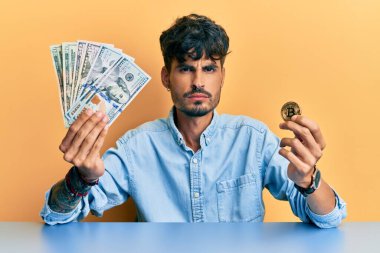 Elinde dolar tutan İspanyol asıllı, Bitcoin 'den şüphelenen ve gergin genç bir adam sorun yüzünden surat asıyor. negatif kişi. 