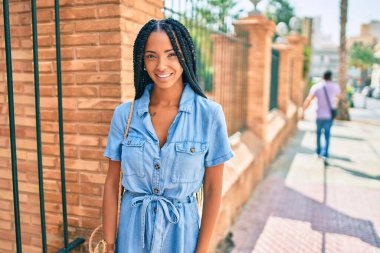 Genç Afrikalı Amerikalı kadın gülümseyerek şehirde mutlu mesut yürüyor..